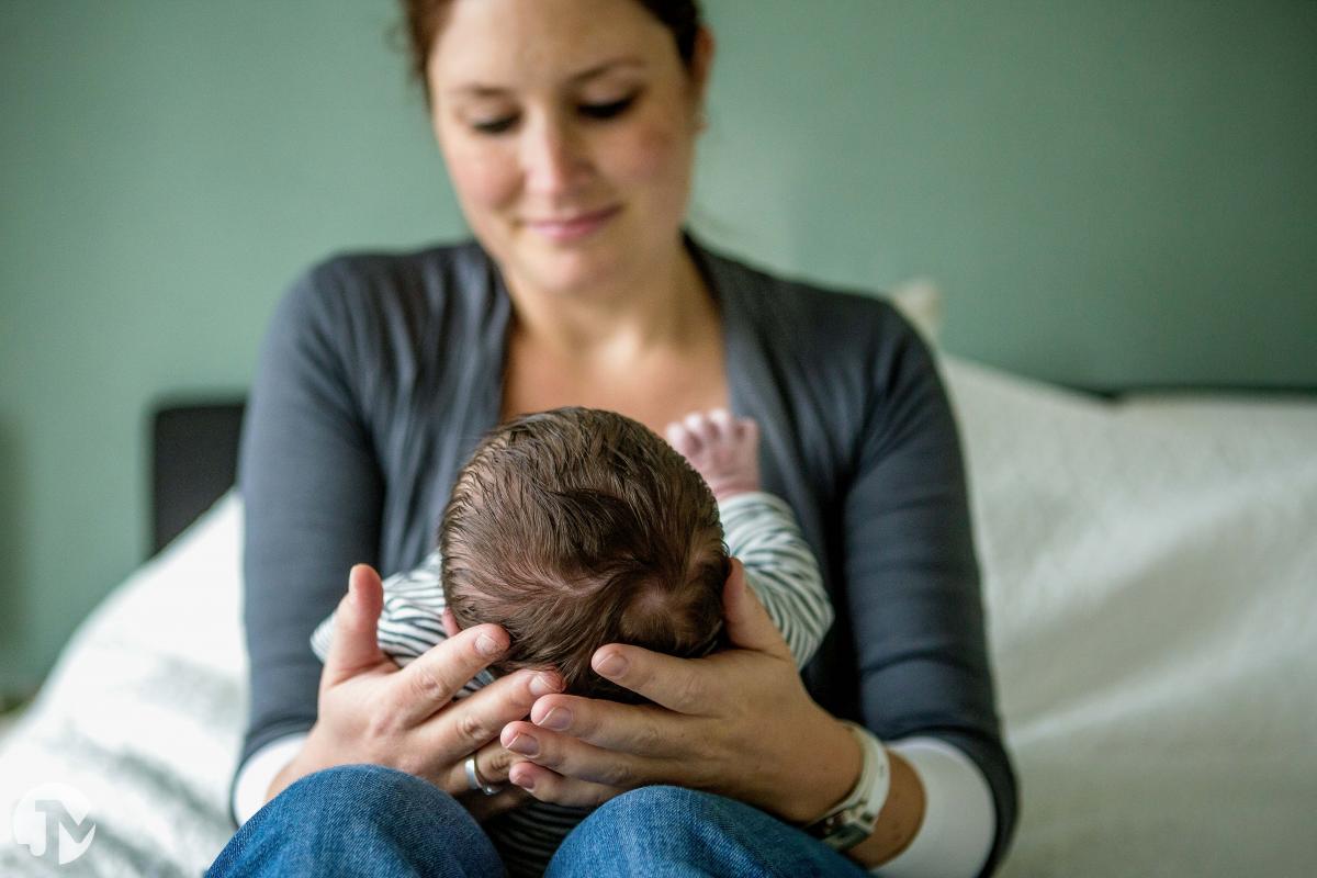 Moeder heeft haar pasgeboren baby op schoot.