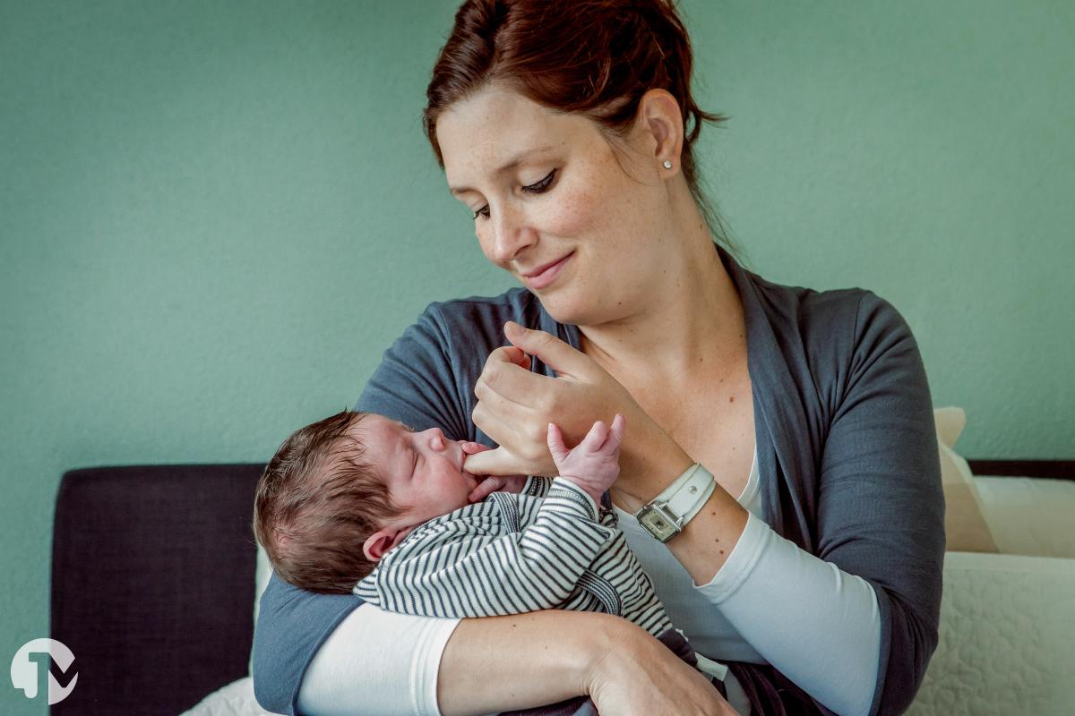 Moeder laat baby rustig worden door hem op haar pink te laten zuigen tijdens de babyshoot.