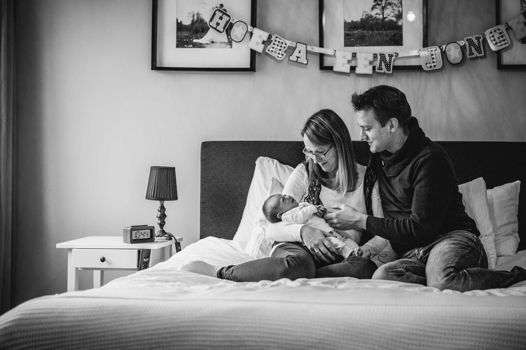 Ouders gezamenlijk op bed met hun pasgeboren baby