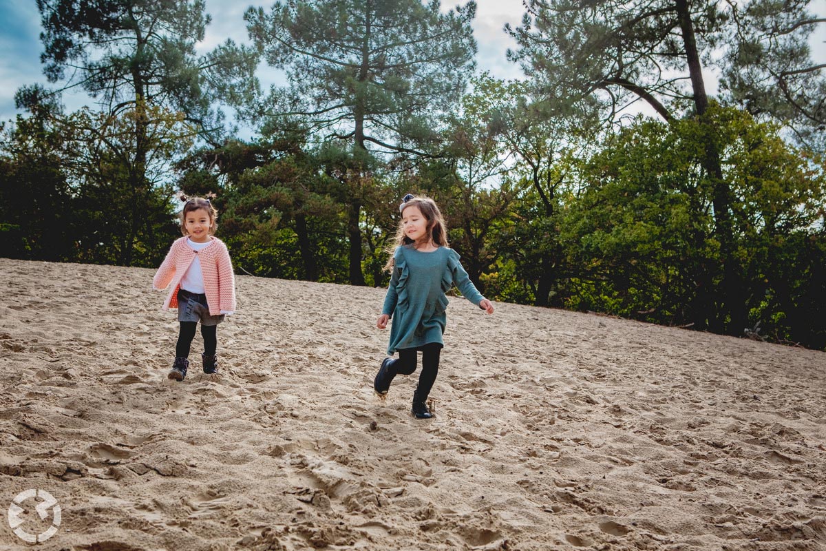 Twee meisjes rennen een zandheuvel af.