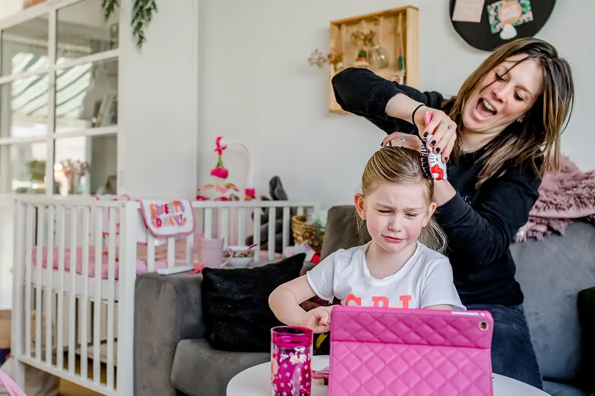 Moeder maakt paardenstaart bij dochter die het niet leuk vindt.