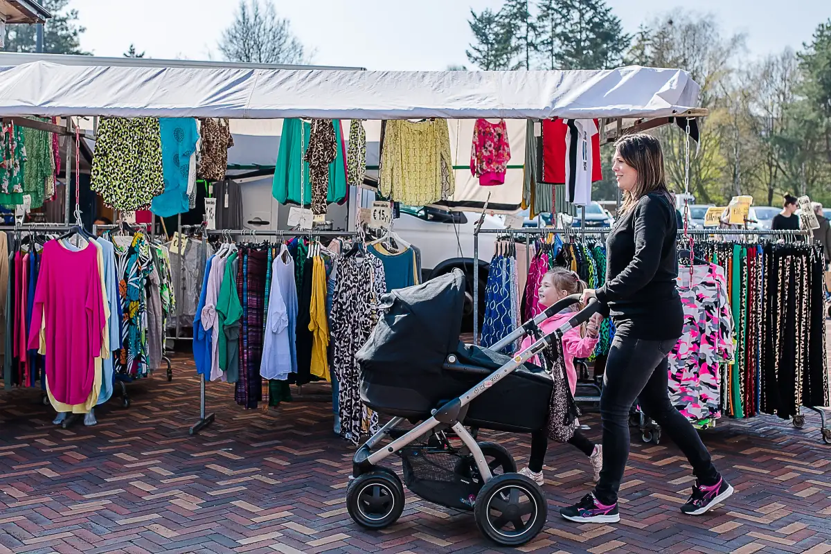 Moeder loopt met dochter en babywagen loopt over de markt in Tilburg.