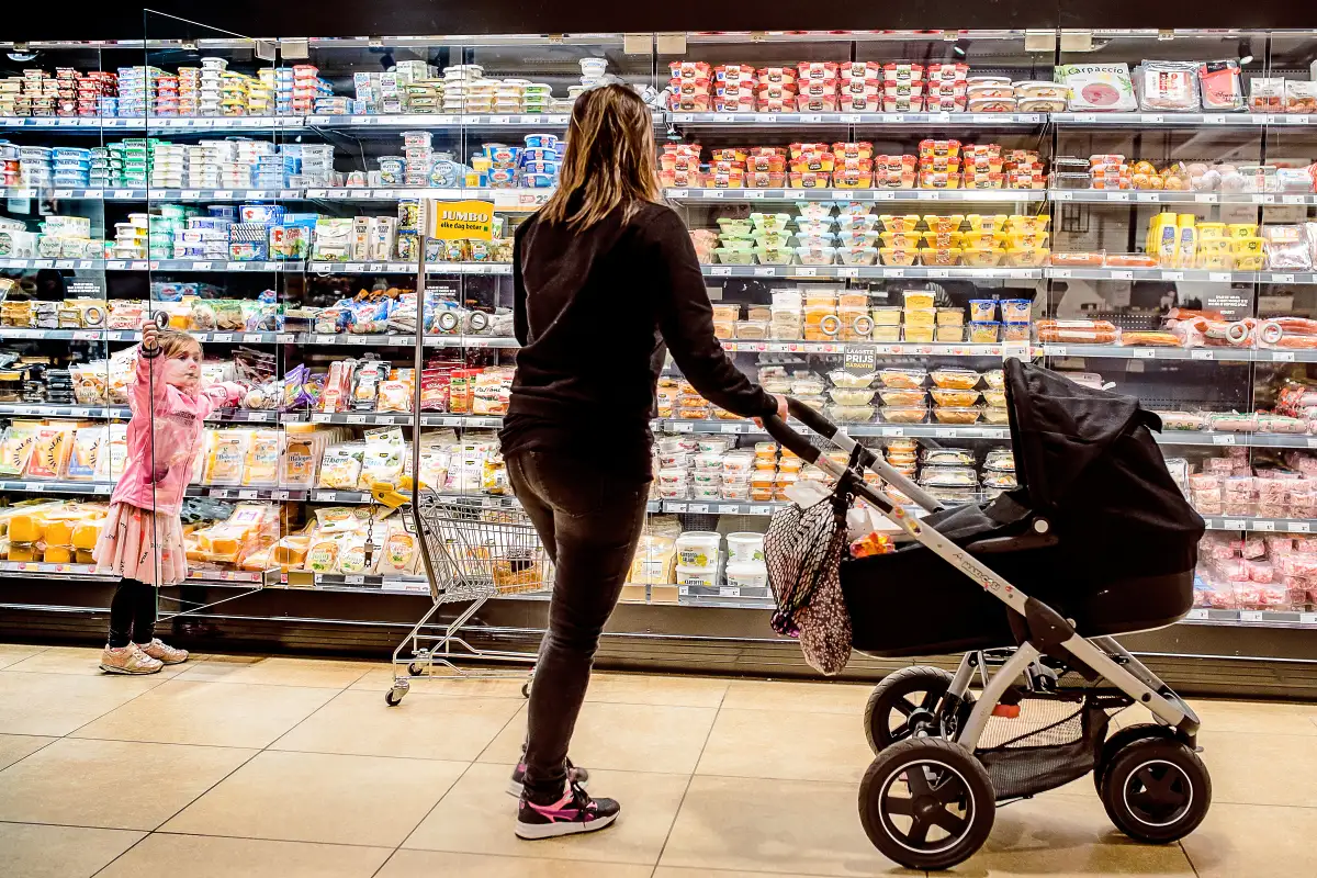 Moeder met dochter en babywagen in de supermarkt.