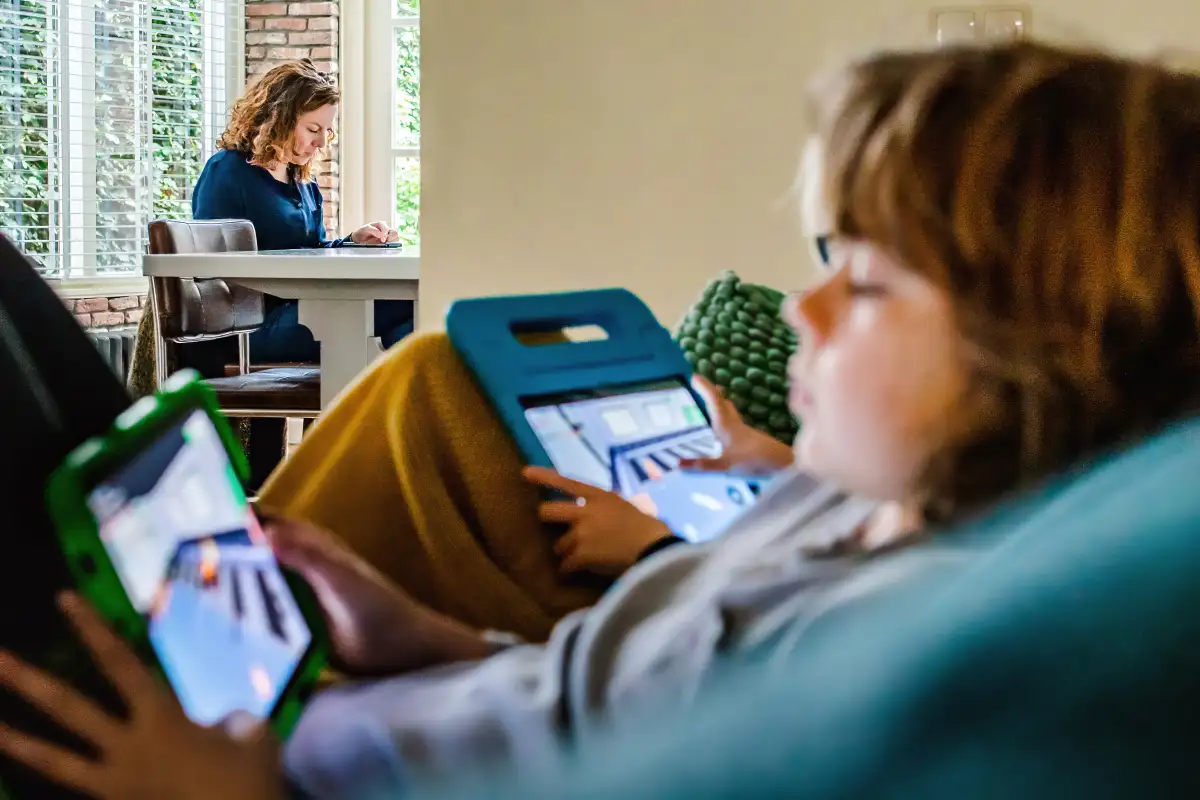 Moeder aan tafel met op de voorgrond kinderen op iPad.