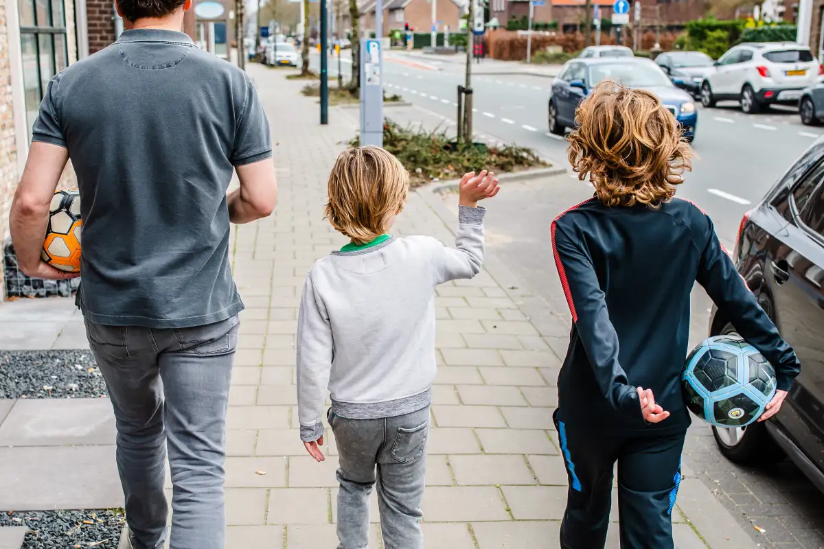 Vader met twee zoontje lopen over straat tijdens een fotoreportage.
