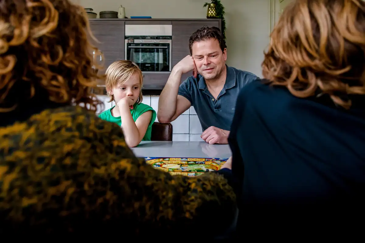 Gezin speelt Ganzenbord tijdens niet geposeerde fotoreportage.
