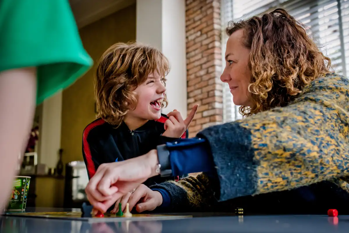 Gezin speelt Ganzenbord tijdens niet geposeerde fotoreportage.