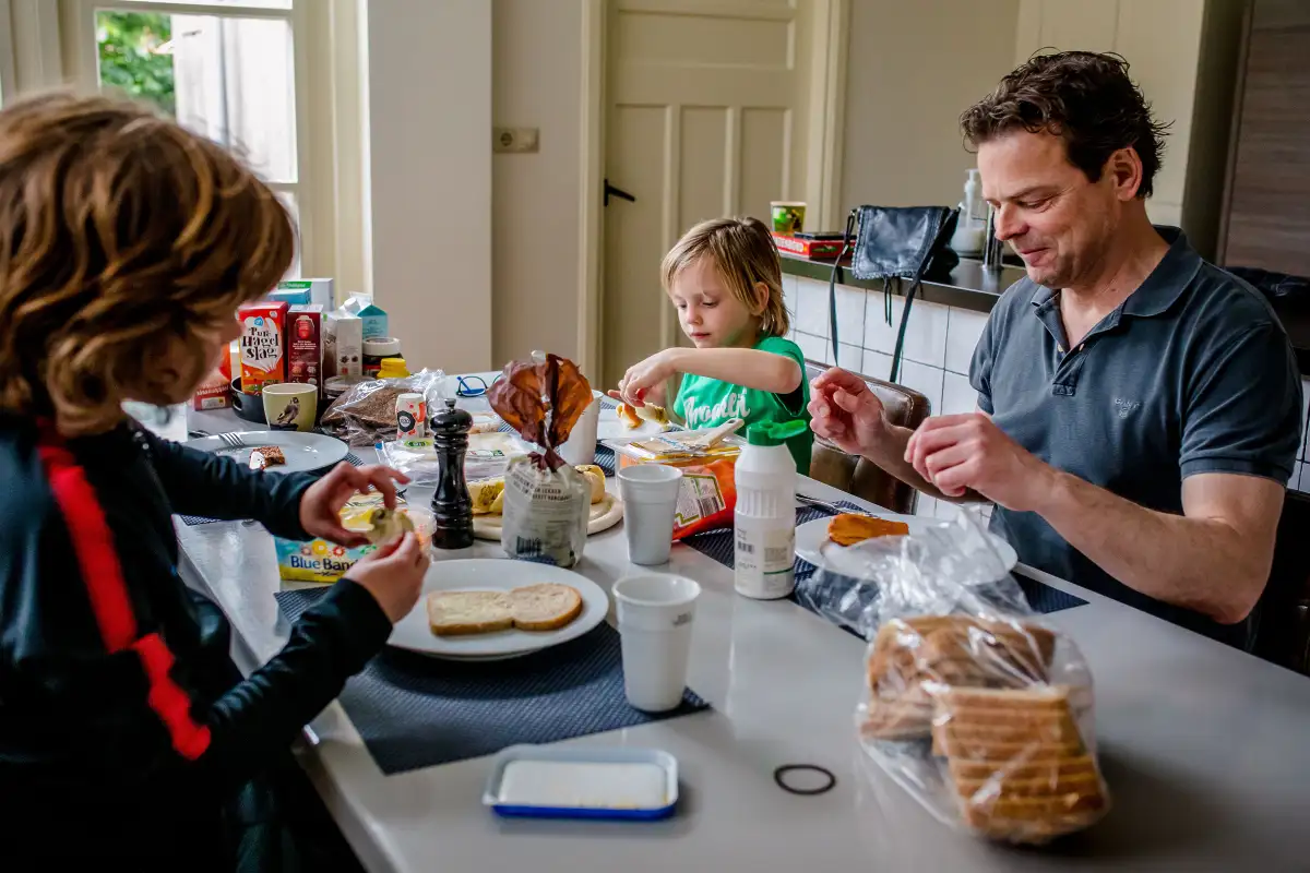 Gezin eet lunch aan de keukentafel tijdens een Day in The Life fotoreportage.