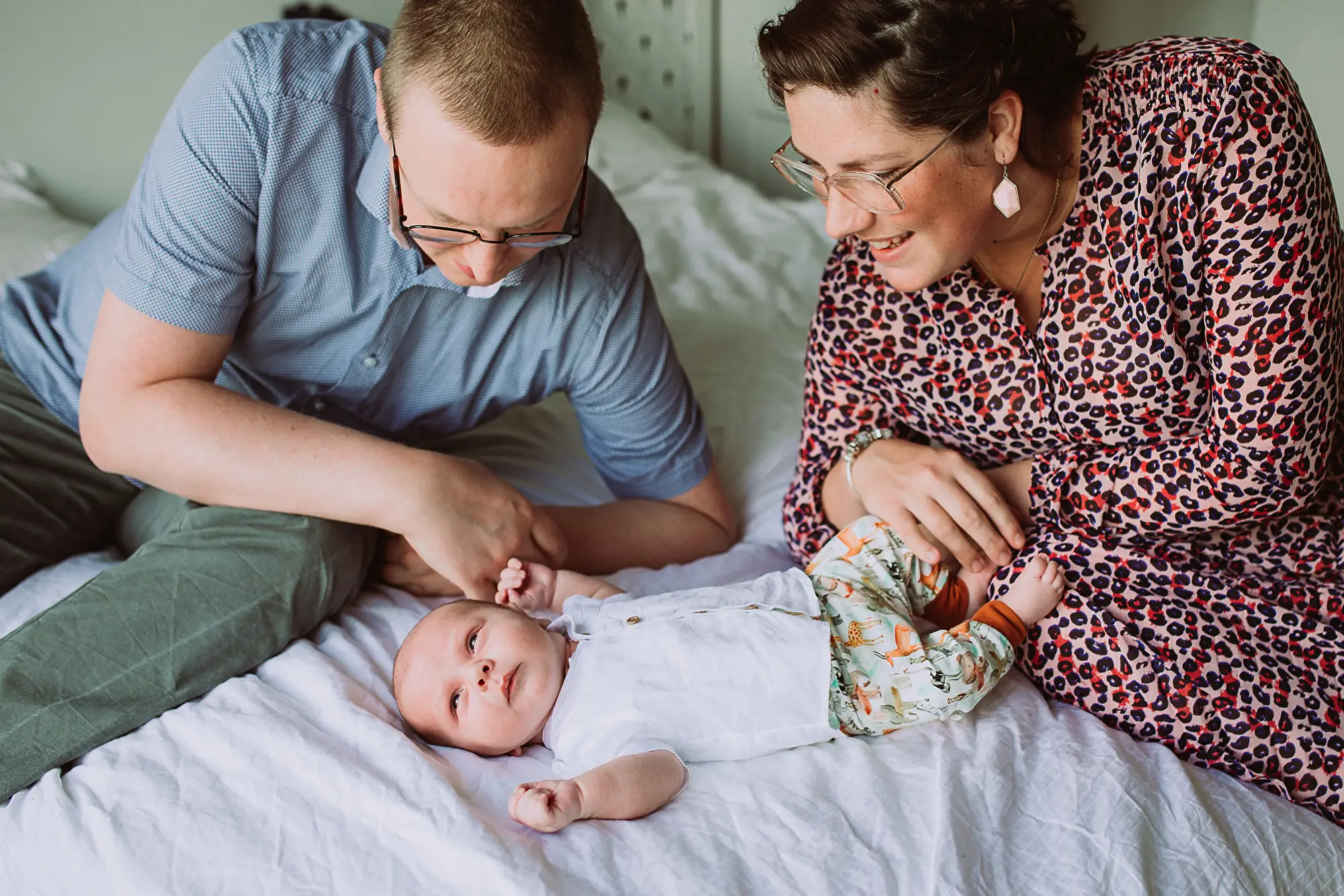 Vader en moeder met baby op bed tijdens een baby fotoshoot.