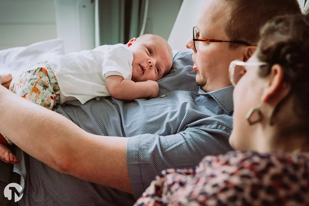 Ouders knuffelen met baby op het bed tijdens de fotoshoot