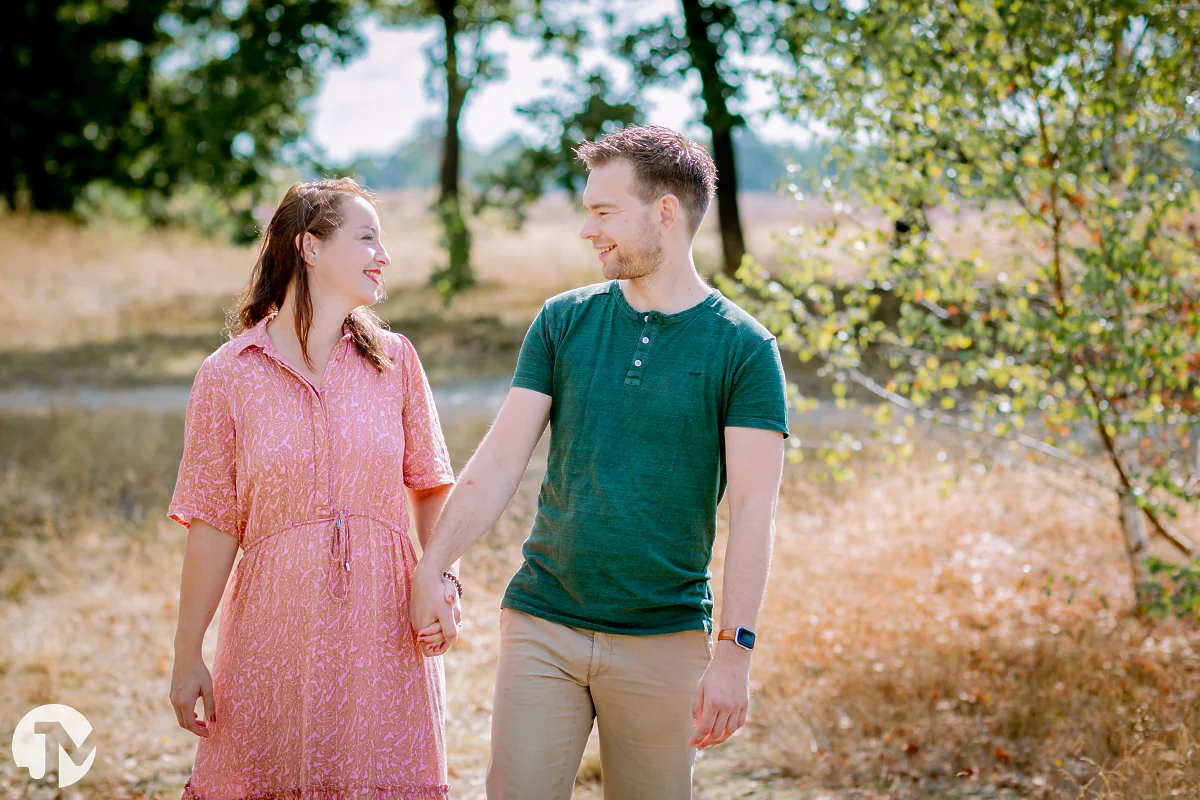 man en vrouw lopen door de loonse en drunense duinen en kijken elkaar lachend aan