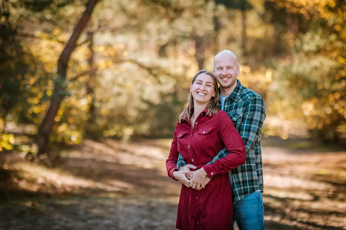 Man en vrouw kijken elkaar lachend aan tijdens een fotoshoot in de Vrachelse Heide in Oosterhout.