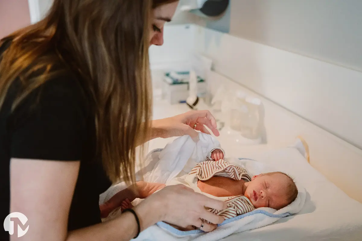 moeder kleed haar pasgeboren baby aan op het aankleedkussen