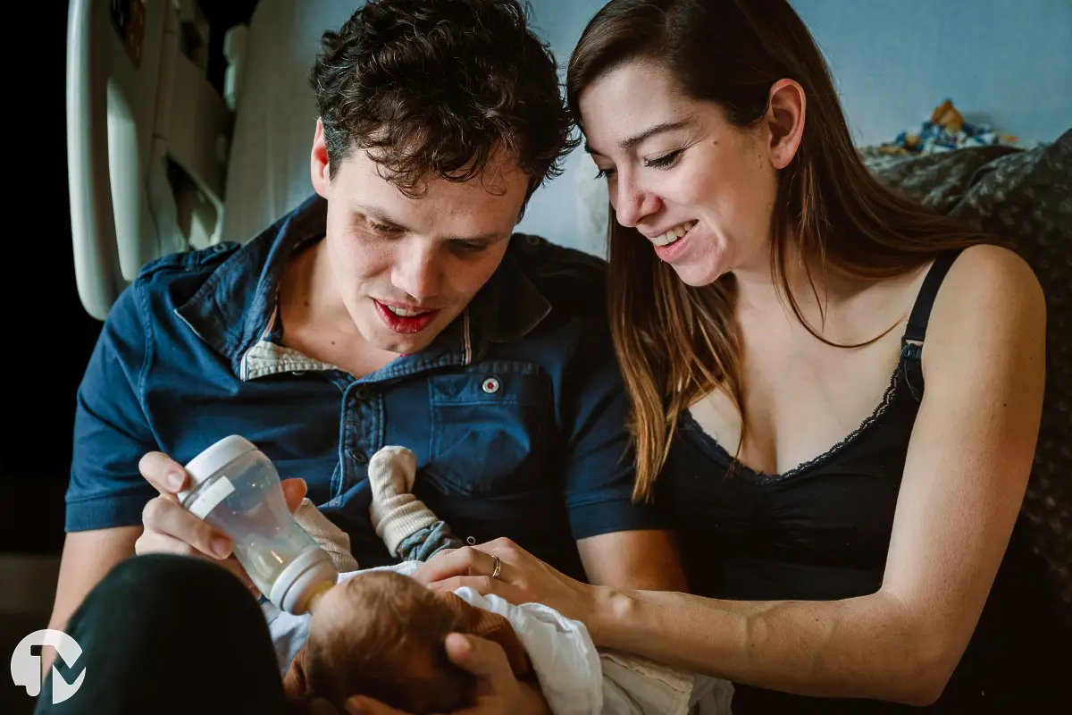 ouders voeden samen de baby met een flesje in het ziekenhuisbed