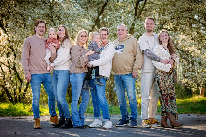 Familie poseren staand op een buiten locatie in de lente.