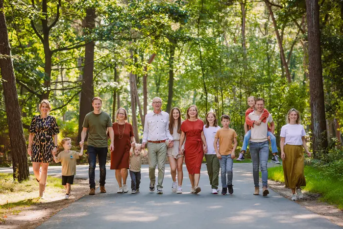 Grote familie loopt hand in hand tijdens een familieshoot door fotograaf uit Breda.