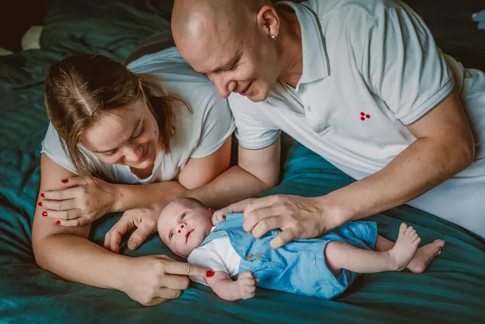 Jonge ouders hebben aandacht voor hun baby op het grote bed.