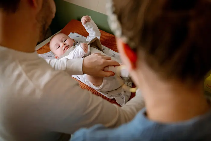 Baby wordt op commode verzorgd door ouders tijdens een newbornshoot.