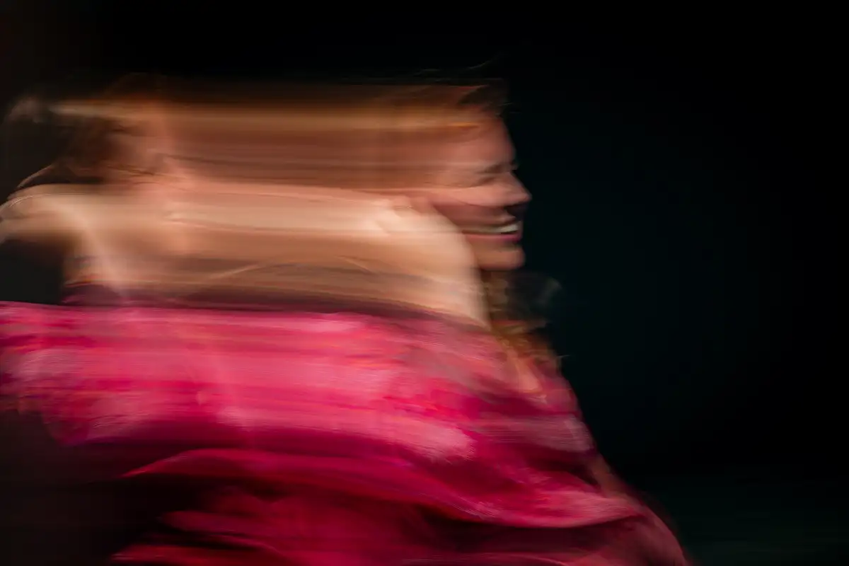 Creatief bewogen foto van kleurrijk persoon bij een donkere muur.