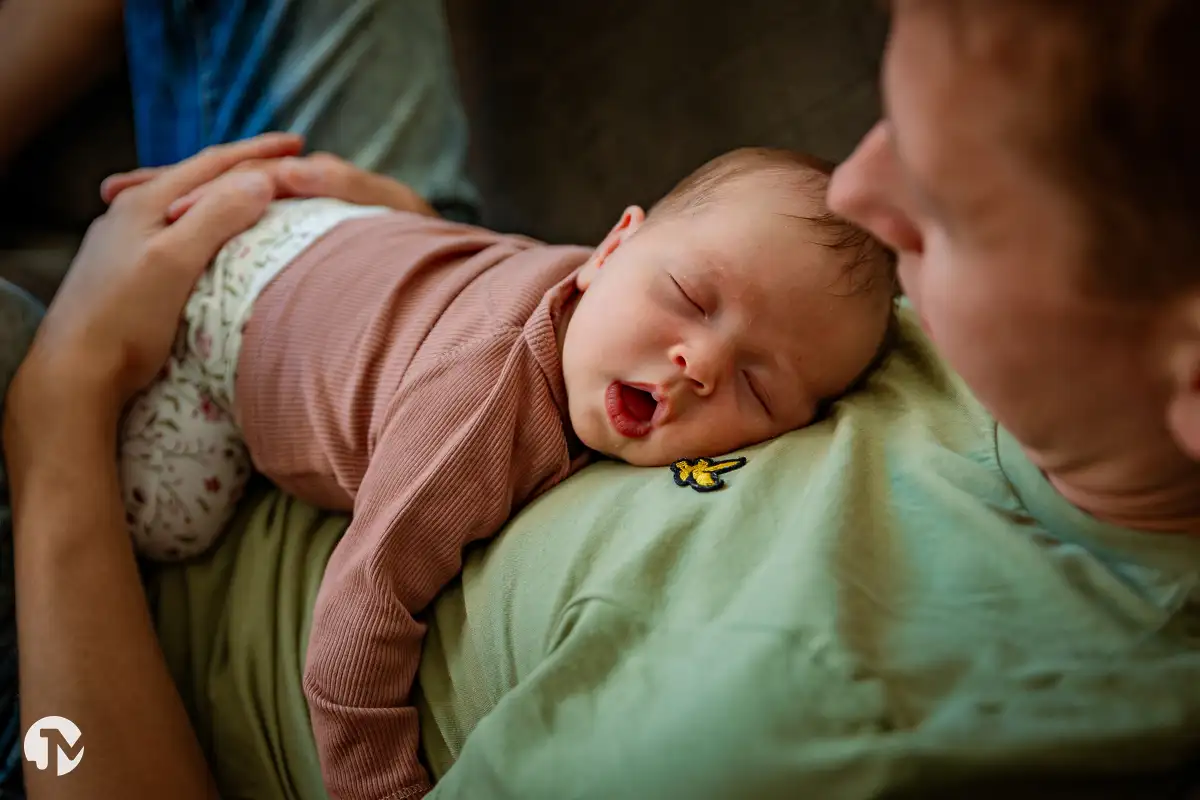 Baby slaapt bij vader op de borst tijdens een fotoshoot aan huis