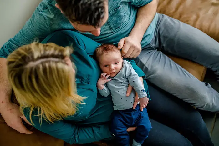 Ouders knuffelen met hun baby op de bank.