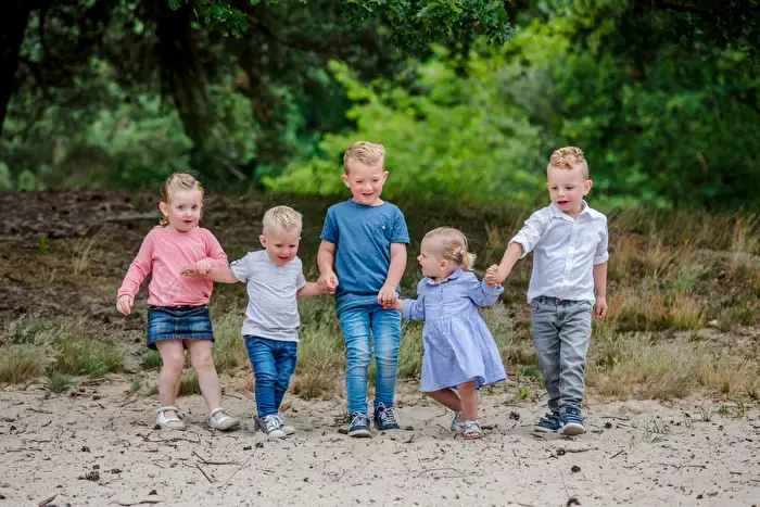 5 kleine kinderen lopen hand in hand in de natuur.