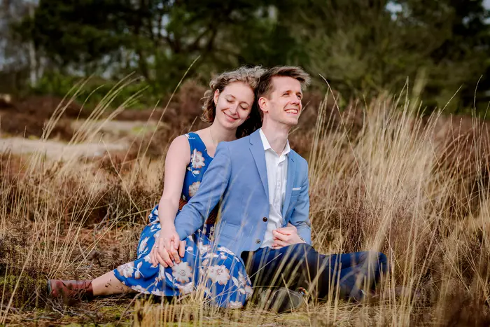 Verliefd stel zit op de grond in de duinen en genieten van elkaar tijdens een lovshoot.