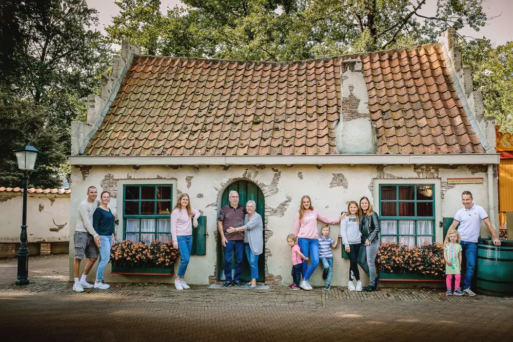 Familie poseert uit elkaar voor een huisje op het Anton Pieckplein in de Efteling.