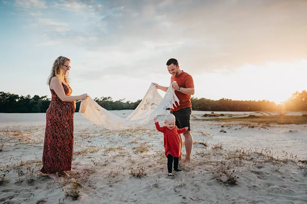  Zwangershapsshoot met gezin in de duinen bij avondlicht.