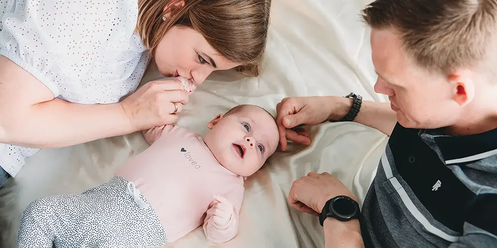 Zwangere vrouw in een roze jurk zit op rood gras en glimlacht rustig, vastgelegd in sfeervolle portretfotografie tijdens een natuurlijke zwangerschapsshoot