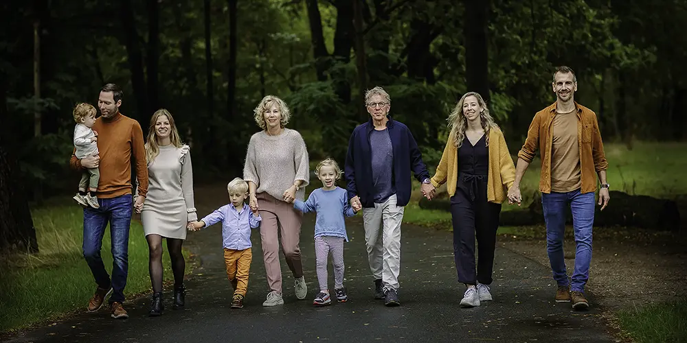 Zwangere vrouw in een roze jurk zit op rood gras en glimlacht rustig, vastgelegd in sfeervolle portretfotografie tijdens een natuurlijke zwangerschapsshoot